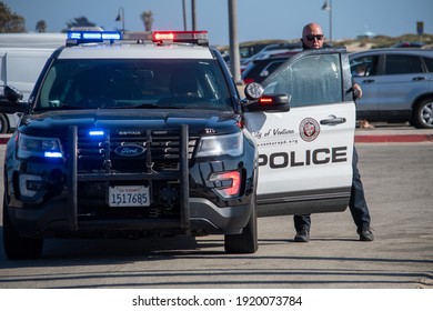 Ventura, California, United States -  August 7, 2020: An officer from the City of Ventura Police Department exits his vehicle to conduct a search of a suspect's vehicle at Ventura Harbor. 