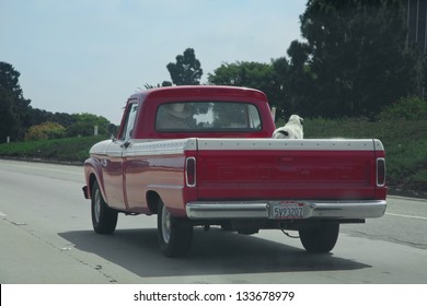 VENTURA - SEPTEMBER 15: Red pickup truck with dog in back down Route 101 on September 15, 2011 in Ventura, CA