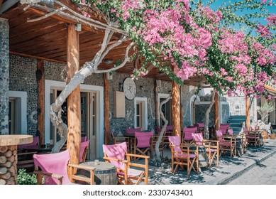The veranda of the summer cafe with pink armchairs is entwined with pink flowers. - Shutterstock ID 2330743401