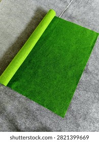 Verdant Rows: An Array of Plain Green Carpet Rolls
​ABOUT
​This clean, studio-styled collection photograph presents a refreshing, orderly arrangement of plain, unpatterned green carpet and rug rolls, creating an abstract study in solid natural color blocking and cylindrical geometry. The styling is clinical and minimalist, showcasing slender and heavy-duty rolls of textile flooring in various luminous shades of emerald, forest green, and lime against a clean backdrop.
​Texturally, the image captures the dense, non-woven matrix of heavy synthetic fibers designed for commercial and exhibition flooring. The surface of each roll is matte and velvety, absorbing directional light uniformly while casting soft, rounded contours along the curved spines of the cylinders. The microscopic irregularity of the matted threads provides a warm, tactile contrast to the rigid, clean-lined composition. This high-impact visual asset serves as a versatile background for modern interior design, commercial flooring catalogs, and corporate architectural portfolios.