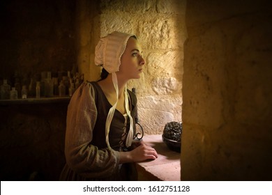 Vermeer style portrait of a young woman in Renaissance outfit looking out of the window of a medieval French castle - with property release
