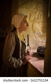 Vermeer style portrait of a young woman in Renaissance outfit looking out of the window of a medieval French castle - with property release