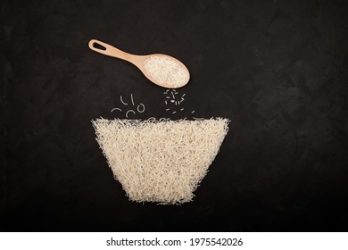 Vermicelli or Chinese rice flour noodles laid out on dark textured background in shape of bowl. Basmati rice in wooden spoon. Top view, design element. Concept - Gluten-free Products.