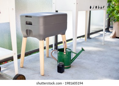 A vermicomposting system (worm composter) sits on an apartment balcony with other patio planters. Worms eat food scraps and produce worm castings and worm tea to be used as fertilizer. Redirect waste.