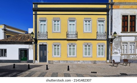 Vernacular architecture: Neoclassical two story townhouse-black edged yellow facade-closed green wood door-white PVC windows-metal railing balcony and balconets-plain pediments. Faro-Algarve-Portugal. - Powered by Shutterstock