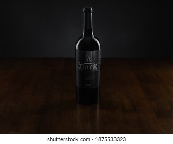 Vero Beach, Florida; USA; Dec. 7, 2020. A Bottle Of A Dark Red Wine Blend Is Placed In The Center Of A Rosewood Table. The Image Has Dark And Moody Lighting. Copy Space.