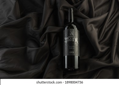 Vero Beach, Florida; USA; Dec. 7, 2020. A Flat Lay, Top Down View Of A Bottle Of Apothic Dark Red Wine. The Wine Bottle Is Photographed On A Wrinkled Silk Cloth Surface. Dark And Moody Lighting.