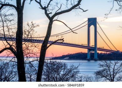 Verrazzano-Narrows bridge in Brooklyn and Staten Island, NYC shortly before sunset, with trees in the foreground