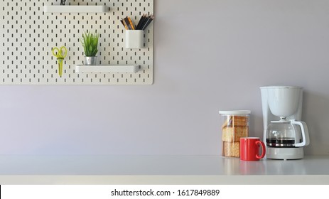 Versatile table in the morning vibe including coffee maker, coffee cup, biscuits is on the table  potted plant, pencil holder and scissors on the white shelf. - Shutterstock ID 1617849889