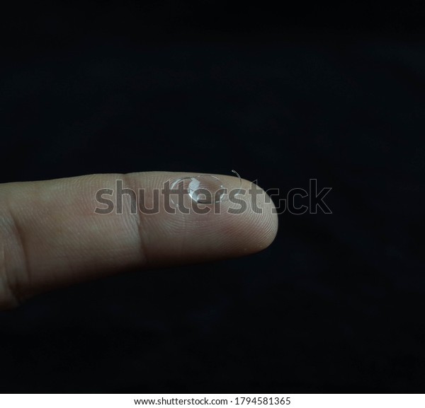 vert tiny\
lens of eye cataract surgery on finger\
tip