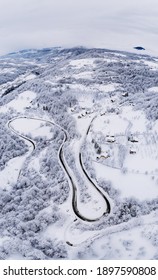 A Vertical Aerial Shot Of A Beautiful Winter Landscape With A Long Winding Road In The Countryside