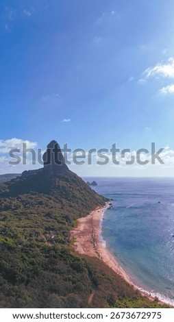 Vertical aerial view of Morro do Pico, the tallest peak in Fernando de Noronha, Brazil, rising above lush greenery and the turquoise Atlantic Ocean