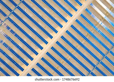Vertical aerial view of a photovoltaic solar panel farm generating sustainable renewable energy in a desert power plant.
