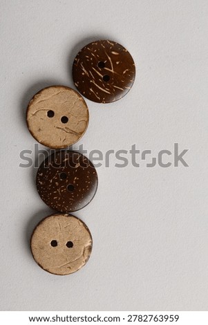 Vertical background with coconut shell buttons along edge, natural sewing supplies for sustainable fashion
