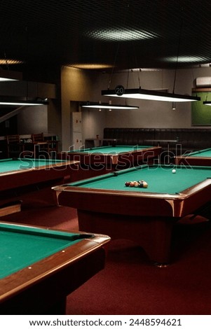 Vertical background image of low lit pool club with several billiard tables and no people copy space