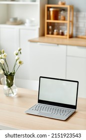 Vertical Background Image Of White Laptop Screen On Wooden Table In Kitchen Decorated With Fresh Flowers In Spring, Copy Space