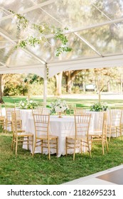 A vertical beautiful view of chairs around white tables at an outdoor wedding venue