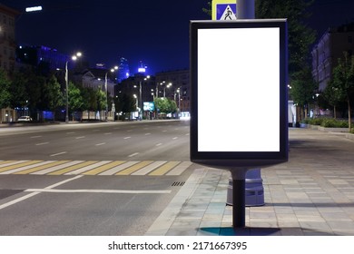 Vertical Billboard Advertising In The Night City. Sky Glows From The Neon Illumination Of The City. Mock-up.