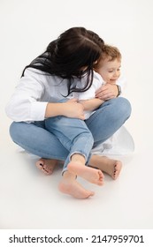 Vertical of black haired woman and little boy, hugging, having fun together. White background. Cuddling and sitting