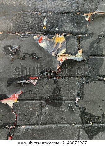 Vertical black painted peeling urban wall with exposed graffiti pain texture