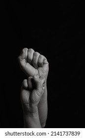 Vertical Black And White Image Of Two Arms With Clenched Fists Coming Out From Below. Close Shot Of A Woman's And A Man's Arm With Their Fingers Closed Together Leaving Copy Space.