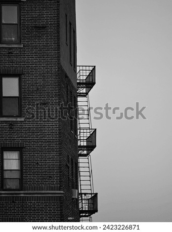 Vertical black and white photo of a brick building and fire escape