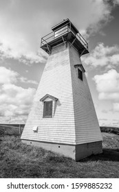 A Vertical Black And White Photo Of A Classic, 19th Century Wooden Lighthouse Under Large Storm Clouds.