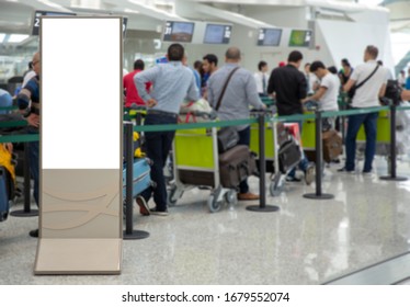 Le panneau d'affichage d'informations vierges verticales se moque de l'écran blanc et de la file d'attente des passagers avec les bagages à l'embarquement à l'aéroport. Arrière-plan flou.