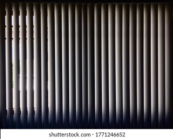 Vertical blind curtain. Behind the dark vertical blinds curtain. Inside the dark room behind the vertical white blinds.