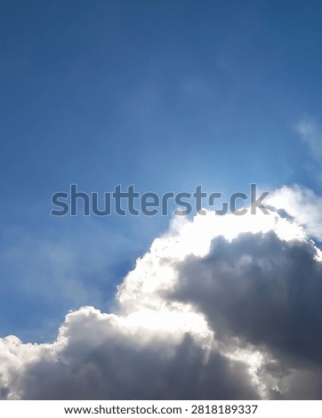 Vertical blue sky with luminous cloud edge and soft crepuscular rays creating a natural background.