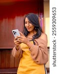 vertical brown-skinned working latina woman checking her cell phone at her business in la paz city bolivia - work concept