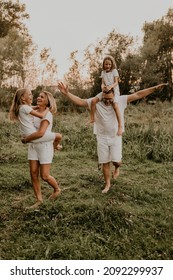 Vertical cheerful happy family dad mom daughters have fun playing summer outdoors together. father mother hugging sisters children park. parents tickle child. blonde child sitting shoulders - Shutterstock ID 2092299937