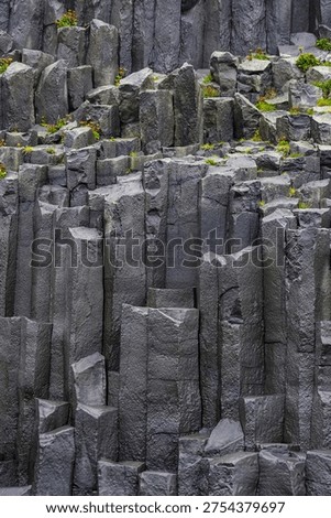 Vertical cliffs - iconic pillars - landmark next to Halsanefshellir Cave. Unique rock formations - basalt columns in the Reynisfjara black sand beach, close up. Vik, Iceland, South Coast. The beach can be very dangerous, with strong waves and unpredictable currents.