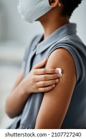 Vertical Close Up Of African-American Child Getting Vaccinated In Clinic And Holding Sterile Cotton Ball On Shoulder