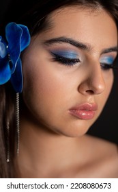 Vertical Close Up Charming, Mysterious, Romantic Brunette Woman With Make Up And Blue Orchid Flowers In Hair Look Down. Perfume, Soft Flavor For Females. Skin And Body Care. Fragrance Cosmetic Product