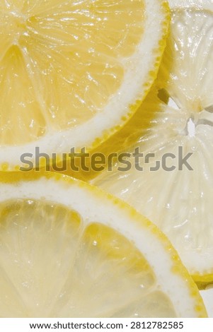 Vertical close up of overlapping fresh lemon slices forming a vibrant citrus background. Bright natural texture suitable for vitamin C