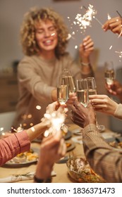 Vertical Close Up Of People Toasting With Champagne Glasses While Enjoying Dinner Party With Friends And Family And Holding Sparklers