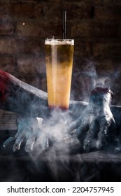 A Vertical Closeup Of A Cocktail Against Creepy Hand Mannequins In Smoke