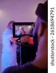 Vertical closeup of director monitoring shot on camera while actress performs in elaborate costume during studio filming session