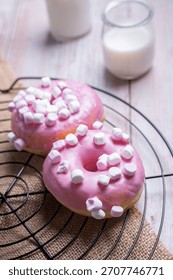 A vertical closeup of donuts with marshmallows next to glasses of milk