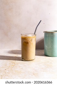 A Vertical Closeup Of A Glass Of Iced Frappe With Vanilla On The Stone Tabletop With Metal Straw