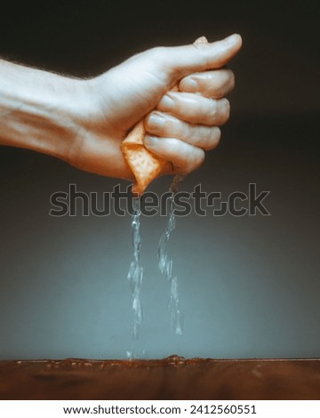 A vertical closeup of a hand squeezing a sponge wipe.
