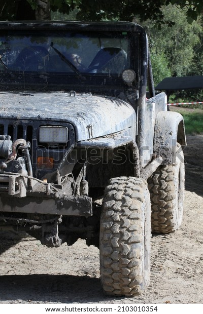 A\
vertical closeup of a muddy UAZ car on a rocky\
road
