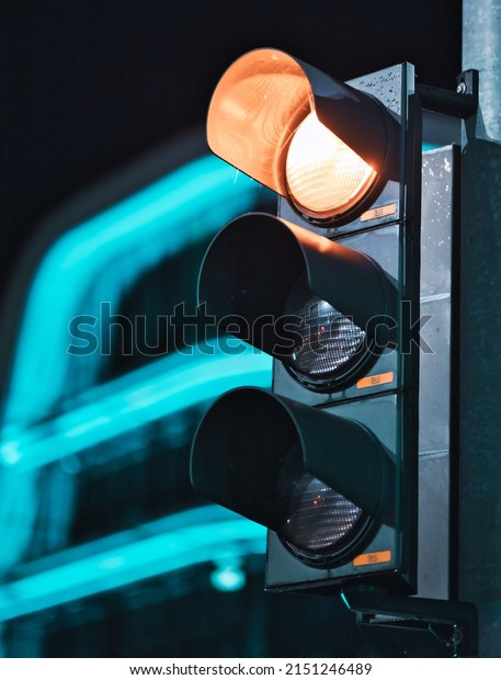 A vertical closeup of the orange light on the\
traffic lights at night