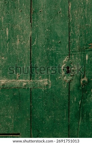 A vertical close-up of a rustic, weathered green wooden door with a decorative keyhole escutcheon