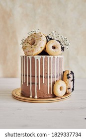 A Vertical Closeup Shot Of Delicious Donut Choco Birthday Cake With Donuts On Top And White Drip