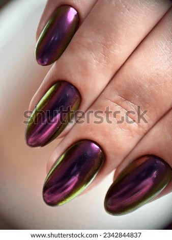 A vertical closeup shot of fingers with a trendy chrome gel nail polish.