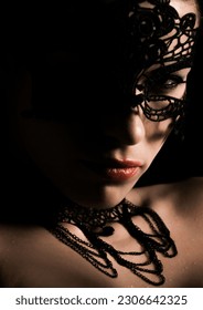 A vertical closeup shot of a mysterious girl face with a dark lacy mask