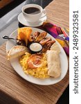 A vertical closeup shot of a typical breakfast with fried plantains, tortilla, eggs and bacon