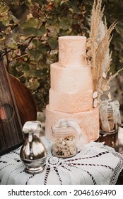 A Vertical Closeup Of A Small Glass Jar Of Cookies With A Big Cake On The Table 